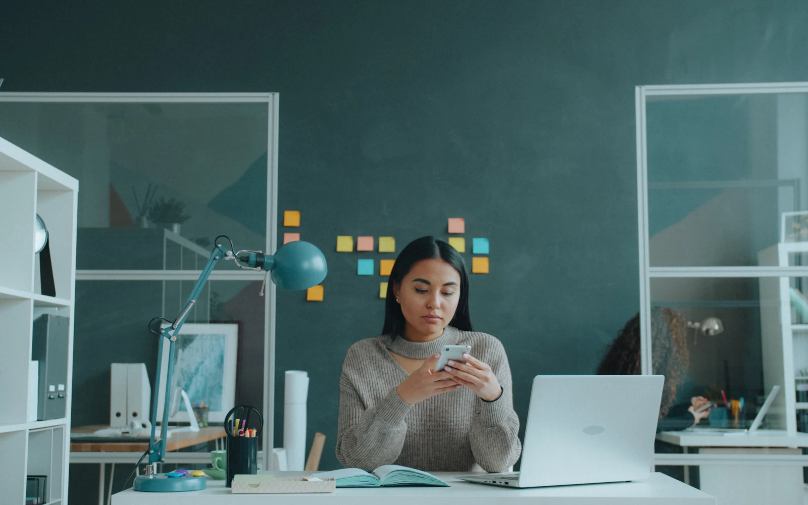 Professional scrolling LinkedIn posts on a phone in an office