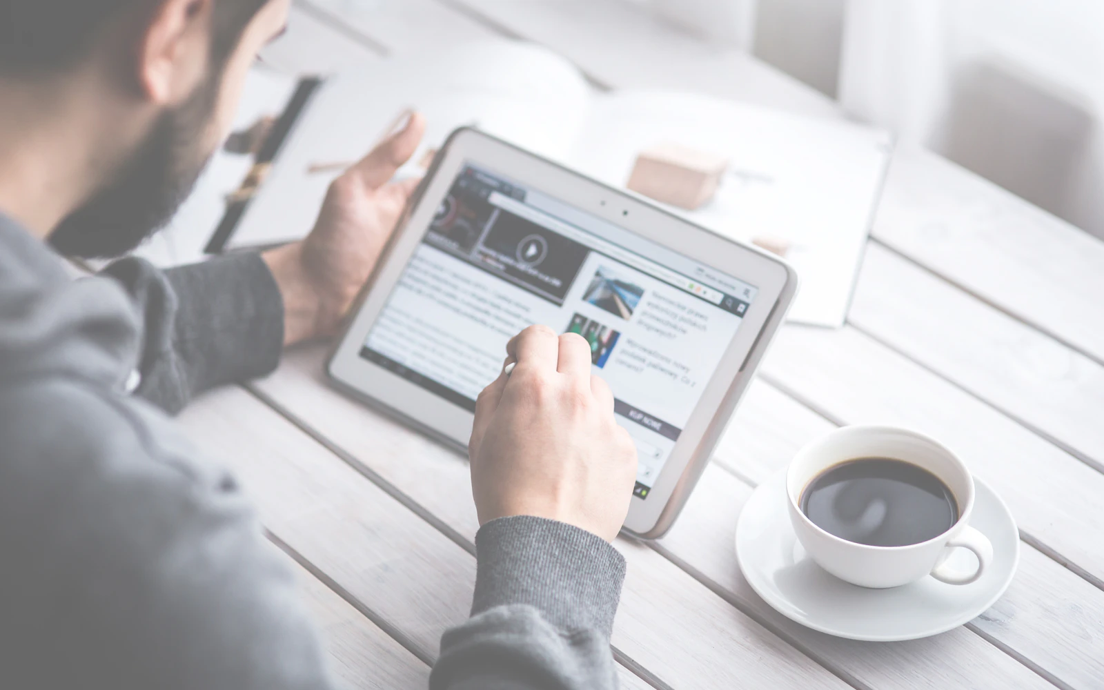 Business reader going through a newsletter on a tablet with coffee
