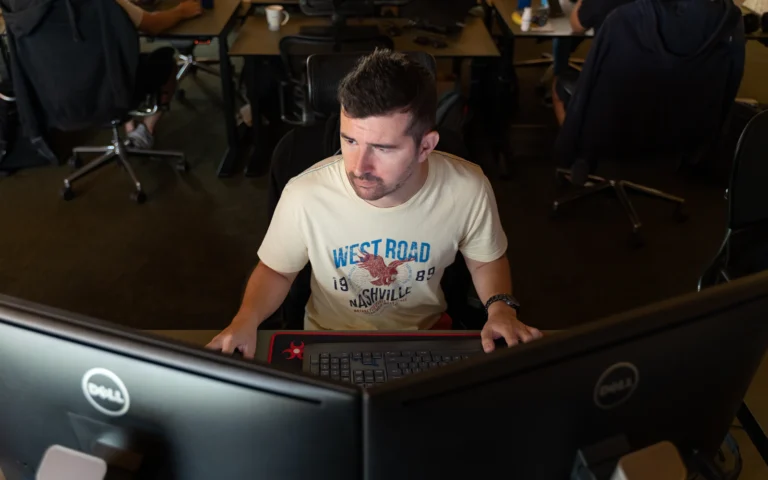 Web designer comparing Webflow vs WordPress on two monitors