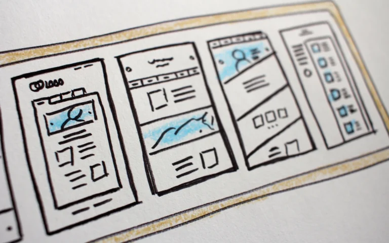 Website redesign checklist next to wireframe sketches on a designer's desk
